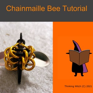 Puede incluir: Un dije de abeja de cota de malla con anillos de metal dorado y negro, alas plateadas y un aguijón negro. La imagen también incluye el texto "Chainmaille Bee Tutorial" y una bruja de dibujos animados leyendo un libro.