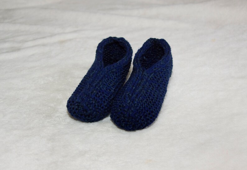 May include: A pair of blue knitted slippers. The slippers are made of a soft, comfortable material and have a simple design.