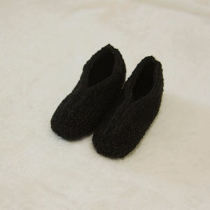 May include: A pair of black knitted slippers. The slippers are made of a soft, comfortable material and have a simple, classic design.