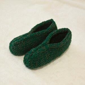 May include: A pair of green knitted slippers with a dark green pattern. The slippers are made of soft yarn and have a comfortable fit.