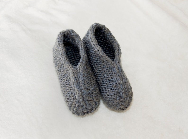May include: A pair of gray knitted slippers. The slippers are made of a soft, cozy material and have a simple, classic design.