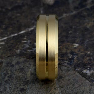 Top view gold tungsten 8mm ring standing upright showing brushed matte finish with thin polished groove running vertically, mens band on concrete