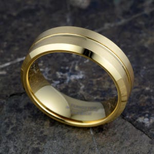 Gold tungsten carbide 8mm ring flat showing full TUNGSTEN CARBIDE engraved interior and brushed exterior with offset polished groove, horizontal view