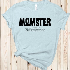 以下が含まれることがあります： 薄い青色のTシャツに、黒い文字で「MOMSTER（mom-ster）n. ママが3まで数えた後どうなるか。」と書かれています。