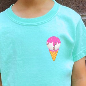 May include: A turquoise t-shirt with a graphic of a baseball-shaped ice cream cone with pink ice cream and sprinkles.