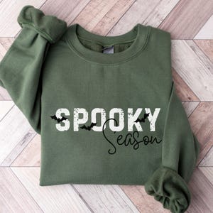 May include: A green sweatshirt with the text "Spooky Season" in white with black bats above and below the text.