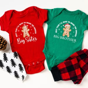 May include: Two baby onesies, one red and one green, with holiday-themed graphics. The red onesie says "Big Sister to be" and the green one says "Big Brother to be". A bib with a black and white tree pattern and red and black plaid pants are also included.