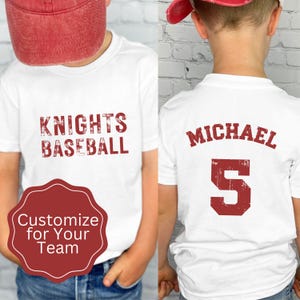 May include: Two white t-shirts with red text. One shirt says "Knights Baseball" and the other says "Michael" with the number "5".