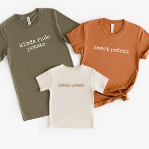 May include: Three t-shirts in olive green, orange, and cream colors. The olive green shirt says "kinda rude potato", the orange shirt says "sweet potato", and the cream shirt says "little potato".