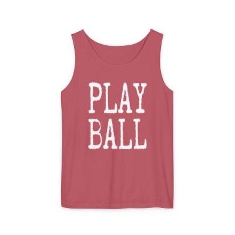 Puede incluir: Una camiseta sin mangas de color rosa polvoriento con el texto PLAY BALL impreso en una fuente blanca desgastada en el centro del pecho. La prenda tiene un cuello redondo y tirantes anchos, ofreciendo un dise&ntilde;o sencillo y limpio.