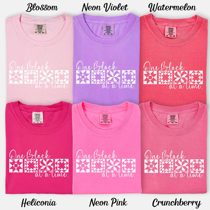May include: Six t-shirts in various shades of pink, purple, and red. Each shirt has the text "One Block at a time" with a geometric design. Colors include Blossom, Neon Violet, Watermelon, Heliconia, Neon Pink, and Crunchberry.