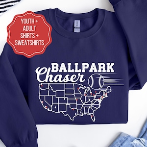 Puede incluir: Sudadera azul marino con un contorno blanco del mapa de los Estados Unidos y el texto "Ballpark Chaser" con un gráfico de béisbol.