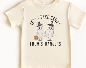 May include: Cream-colored t-shirt featuring a Halloween-themed graphic. The design includes two ghost figures holding hands, wearing witch hats, and carrying a jack-o'-lantern bucket. The text reads "LET'S TAKE CANDY FROM STRANGERS."