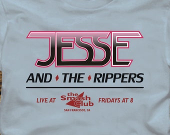 May include: Light blue t-shirt with a graphic design featuring the text "Jesse and the Rippers", "Live at the Smash Club", and "Fridays at 8".