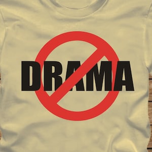 Może przedstawiać: Jasnobeżowy t-shirt z czerwonym kółkiem i przechodzącą przez nie ukośną linią. Wewnątrz koła nadrukowane są czarne litery "DRAMA". Na dole obrazu nadrukowane są białe litery "YELLOW HAZE".