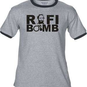 May include: Grey ringer t-shirt with black trim. The shirt displays the text "ROFI BOMB" in a distressed font, along with a man's portrait and a bomb graphic. The tee is made of a soft material.