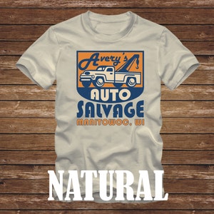 以下が含まれることがあります： ベージュのTシャツに、ビンテージスタイルの牽引車のグラフィックと「Avery's Auto Salvage Manitowoc, WI」のテキストがプリントされています。テキストは青とオレンジです。