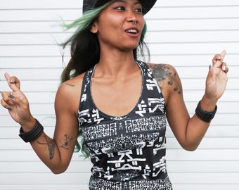 May include: A woman wearing a black and white patterned tank top dress with a black baseball cap. She is wearing a nose ring and has green hair.