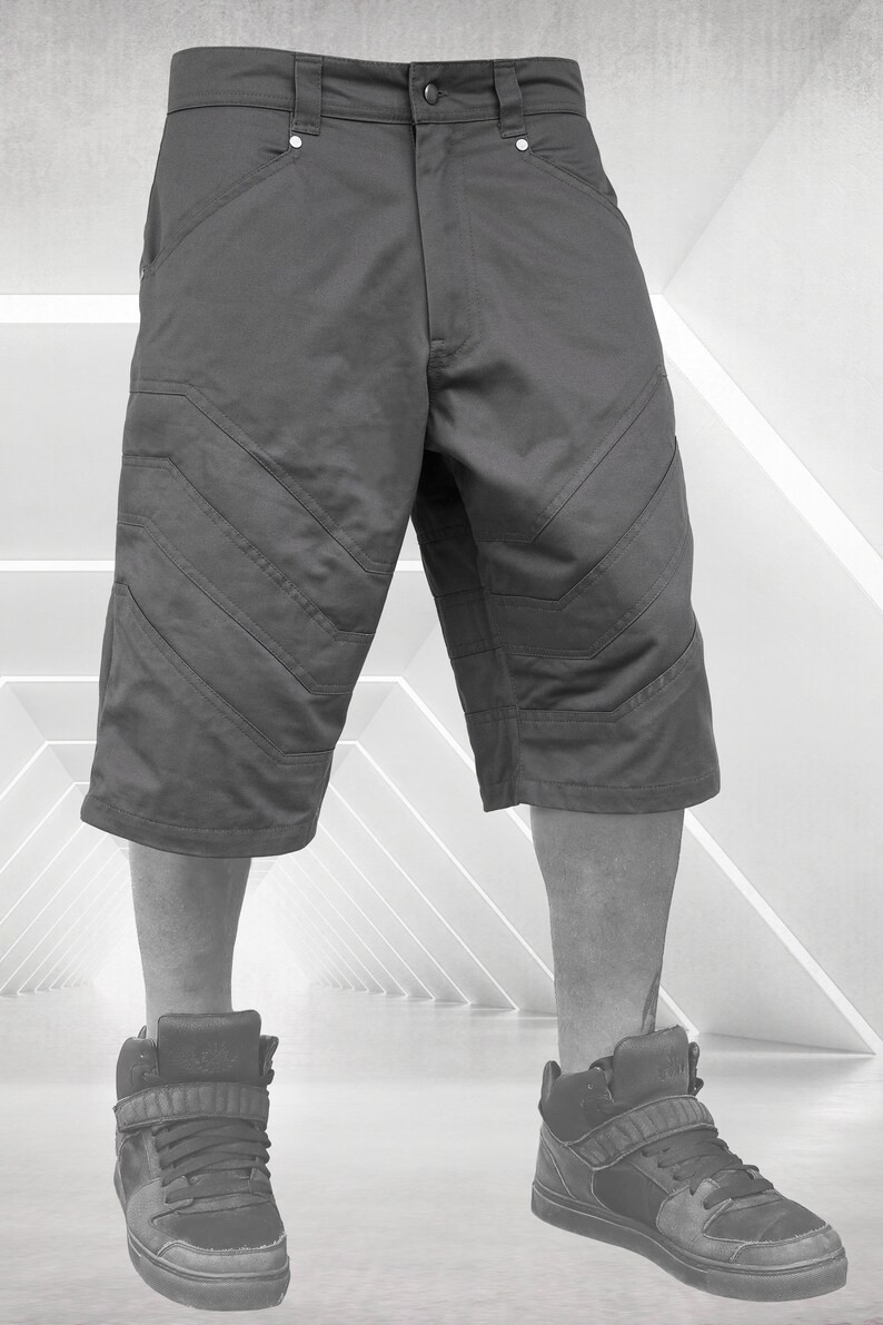 May include: Charcoal gray knee-length shorts with angled stitching details. The shorts have a button closure and pockets. The model is wearing high-top sneakers. The shorts are a modern, casual style.