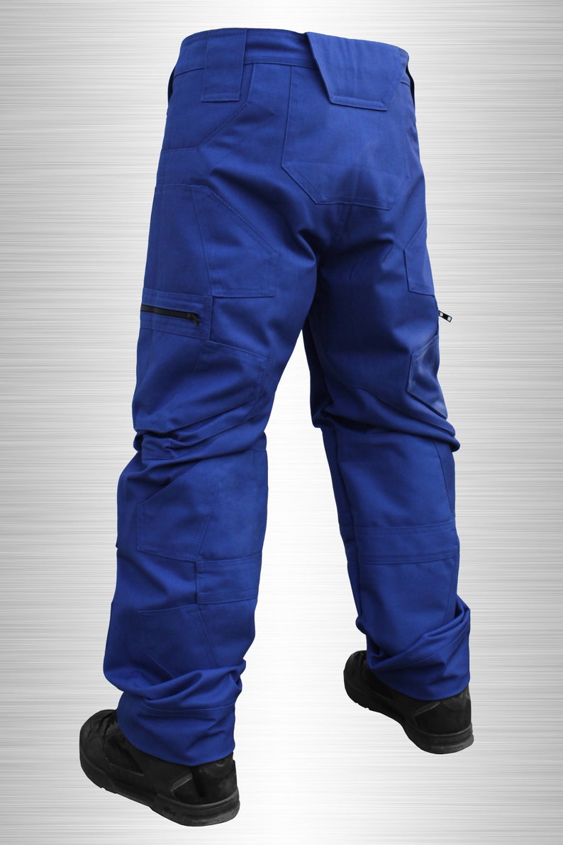 May include: Royal blue work trousers with multiple pockets and a zip closure. The trousers have a structured design and are worn with black work boots. The image is set against a silver gradient background.