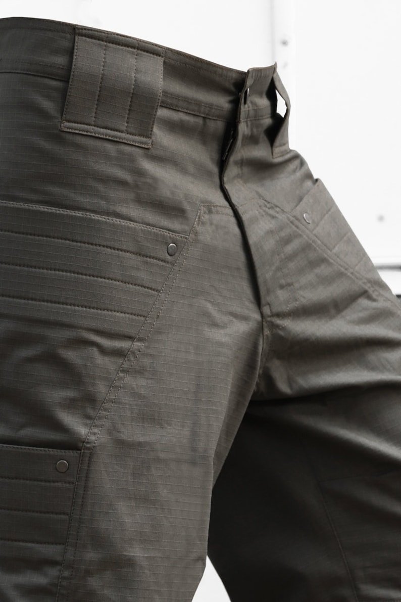 May include: A pair of dark green cargo pants with multiple pockets and a button fly.