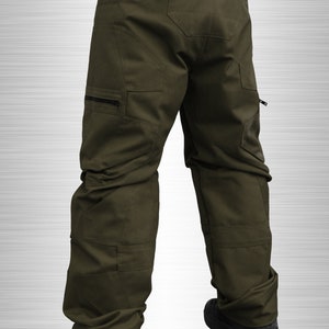 May include: A pair of olive green cargo pants with multiple pockets and a zippered detail on the side. The pants are made of a durable, water-resistant fabric.