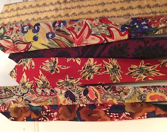 May include: A collection of six patterned neckties in various colors and designs, including floral, paisley, and geometric patterns.