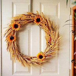 Pu&ograve; includere: Una ghirlanda di grano e girasoli con un tema rustico autunnale. La ghirlanda &egrave; fatta di steli di grano secchi e presenta diversi girasoli gialli.