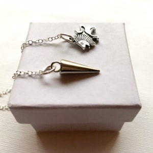May include: A silver chain necklace with two pendants. One pendant is a silver lion, the other is a silver cone.