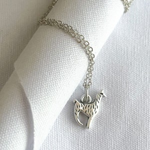 May include: A silver chain necklace with a small, detailed llama pendant.