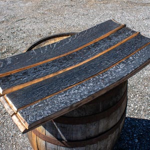 May include: A set of three curved wooden barrel staves featuring a deeply charred, textured black finish on the outer surface and a natural light brown wood tone on the edges, arranged horizontally to form a flat, rectangular surface.
