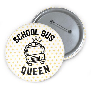 Puede incluir: Un botón redondo con las palabras "SCHOOL BUS QUEEN" en negro, con un dibujo de autobús escolar y una corona. El fondo es blanco con formas de diamantes amarillos. La parte trasera del botón es plateada.