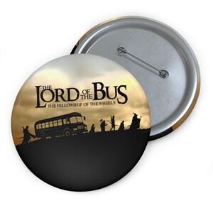 Puede incluir: Un botón redondo con un diseño humorístico. El botón presenta el texto "The Lord of the Bus" sobre una silueta de un autobús escolar y figuras, con la frase "The Fellowship of the Wheels" debajo. El fondo es un degradado de amarillo y marrón.