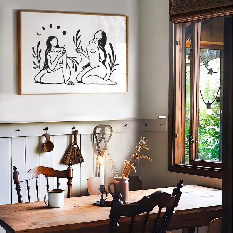 May include: A black and white line art print of two figures in a forest setting. The figures are facing each other and appear to be holding hands. The print is framed and hanging on a white wall.