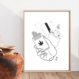 May include: Black and white line art illustration of a hand holding a packet of cigarettes with a marijuana leaf on the front and a lighter with a flame coming out of it.