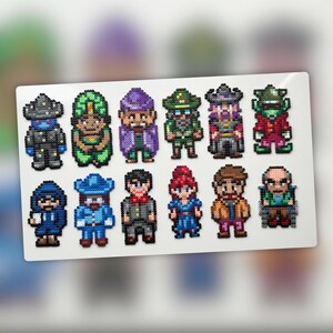 Op de afbeelding: Een verzameling van twaalf pixel art figuren, elk met unieke outfits en accessoires. De figuren zijn gemaakt van kleine, kleurrijke kralen en zijn gerangschikt op een wit rechthoekig oppervlak. De figuren omvatten personages met hoeden, jassen en andere kleding.