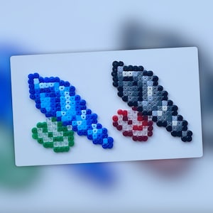 Op de afbeelding: Twee pixel art zwaarden gemaakt met gekleurde kralen. Het zwaard links is blauw met een groene handvat. Het zwaard rechts is zwart met een rode handvat.