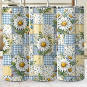 May include: A floral tumbler featuring a patchwork design with daisies, butterflies, and ladybugs. The tumbler has a white straw and a repeating pattern of blue gingham, yellow stripes, and floral squares.