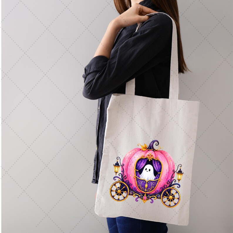 Puede incluir: Un bolso tote blanco con un dise&ntilde;o de carruaje de calabaza rosa y un fantasma dentro. El carruaje tiene detalles dorados, cortinas moradas y ruedas negras. Dos faroles flanquean el carruaje, ideal para Halloween.