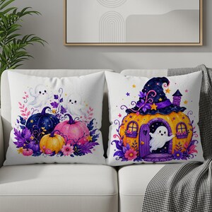 Puede incluir: Dos cojines decorativos con tem&aacute;tica de Halloween. Uno presenta un dise&ntilde;o de calabazas y fantasmas con detalles florales morados y rosas. El otro tiene una casa calabaza con un fantasma y un sombrero de bruja.