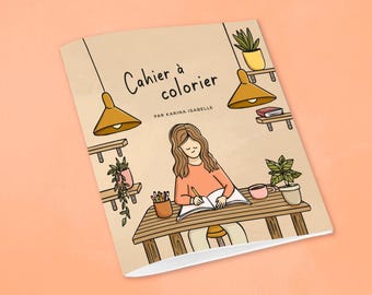 May include: A brown coloring book with the title "Cahier à colorier" and the text "Par Karina Isabelle". The cover features a cartoon illustration of a person sitting at a table with a pencil and a notebook, surrounded by plants and lights.