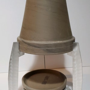 May include: A terracotta pot with a metal stand. The pot is brown with a marbled pattern. The stand is silver and has a round base.