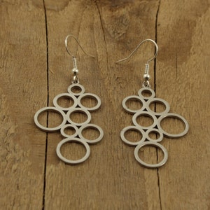Peut inclure: Une paire de boucles d'oreilles en argent avec un motif géométrique de cercles entrelacés.