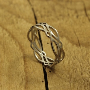 May include: A silver ring featuring a Celtic knot design. The ring is made of metal and has a smooth finish.