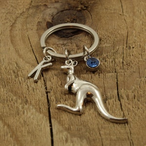 May include: Silver keyring with a kangaroo charm, a letter K charm, and a blue crystal charm.