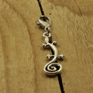 May include: Silver charm in the shape of a curled up lizard with a lobster clasp.