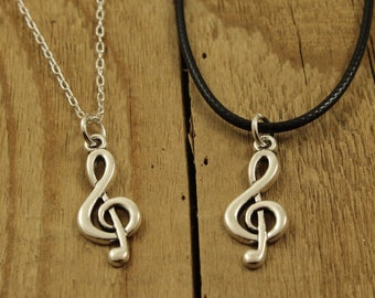 Puede incluir: Dos collares de plata con una clave de sol, uno en una cadena de plata y el otro en un cordón negro.