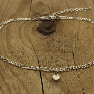 May include: A silver chain anklet with a small heart charm.