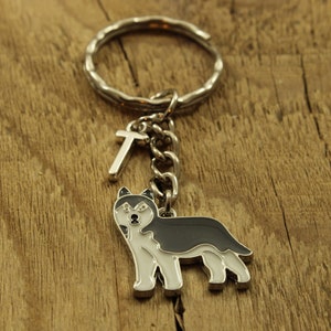 May include: A silver key chain with a black and white husky charm and a silver letter 'T' charm.