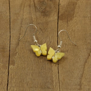 May include: A pair of yellow butterfly earrings with silver hooks.